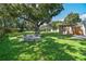 Expansive backyard with lush lawn, mature tree, a stone firepit, and outbuilding at 4009 S Renellie Dr, Tampa, FL 33611