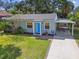 Charming single-story home with a blue front door, manicured lawn, and covered parking at 4009 S Renellie Dr, Tampa, FL 33611