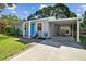 Charming single-story home featuring a bright blue door, a covered carport, and a paved walkway at 4009 S Renellie Dr, Tampa, FL 33611