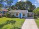 Charming single-story home with a blue front door, manicured lawn, and covered parking at 4009 S Renellie Dr, Tampa, FL 33611