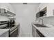 Compact kitchen featuring stainless steel appliances, white cabinets, gray countertops and a stainless hood at 4009 S Renellie Dr, Tampa, FL 33611