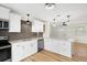 Updated kitchen showcasing white cabinets, modern appliances, tiled backsplash, and wood floors at 4414 W Oklahoma Ave, Tampa, FL 33616