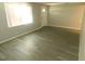 Bright and spacious living room featuring wood-look floors, a window, and a white door at 4417 Kohler St, New Port Richey, FL 34652