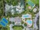 Birds eye view of tennis court, clubhouse, swimming pool, playground, basketball court, and picnic area next to pond at 4716 Butler National Dr, Wesley Chapel, FL 33543