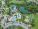 Aerial view showing the community pool, tennis courts, and playground near a serene pond at 4716 Butler National Dr, Wesley Chapel, FL 33543