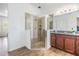 Bright bathroom featuring a glass enclosed shower with decorative tiles and a granite countertop vanity at 4716 Butler National Dr, Wesley Chapel, FL 33543