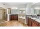 Bathroom with dual sinks, walk-in shower, soaking tub, and wood-look tile floors at 4716 Butler National Dr, Wesley Chapel, FL 33543