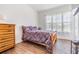 Relaxing bedroom with wood-look floors, floral comforter, and natural light from the windows at 4716 Butler National Dr, Wesley Chapel, FL 33543