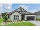 Inviting exterior of home with well-kept lawn, landscaping, and a two-car garage at 4716 Butler National Dr, Wesley Chapel, FL 33543