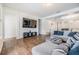 Spacious living room with wood-look floors featuring gray sectional seating and a wall-mounted TV at 4716 Butler National Dr, Wesley Chapel, FL 33543