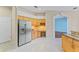 Spacious kitchen with stainless steel refrigerator and tiled floors, adjacent to an arched doorway at 4959 Felecity Way, Palm Harbor, FL 34685
