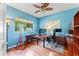 Well-lit home office with wood floors, fan, windows, and multiple monitors and desk space at 4959 Felecity Way, Palm Harbor, FL 34685