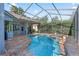 Screened-in pool with attached hot tub surrounded by travertine tile and landscaping at 4959 Felecity Way, Palm Harbor, FL 34685