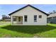 Back exterior view of a home with white siding and black window trim, surrounded by a green lawn at 5701 N 20Th St, Tampa, FL 33610