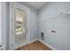 Laundry room featuring gray walls, wood-look vinyl flooring, door to outside, and white shelving at 5703 N 20Th St, Tampa, FL 33610