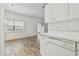 Bright kitchen area with wood-look floors, white appliances and cabinets, and a sliding glass door at 6234 Ashbury Palms Dr, Tampa, FL 33647