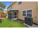 Back patio of home with screened in porch, green grass, and an AC unit at 6234 Ashbury Palms Dr, Tampa, FL 33647