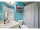 Well-lit bathroom featuring a toilet, sink, vanity, a shower with a white curtain, and blue-painted walls at 7534 Oxford Garden Cir, Apollo Beach, FL 33572