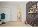 Bright bedroom with tiled floor, white closet doors, a floral accent wall, and an open doorway at 7534 Oxford Garden Cir, Apollo Beach, FL 33572