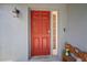Inviting front door with red paint and a sidelight, situated under an overhang for added protection at 7534 Oxford Garden Cir, Apollo Beach, FL 33572