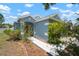 Charming single-story home with a blue exterior, arched entry, and manicured landscaping at 7534 Oxford Garden Cir, Apollo Beach, FL 33572