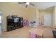 Neutral-toned living room with tile floors, ceiling fan, and large media center for storage and entertainment at 7534 Oxford Garden Cir, Apollo Beach, FL 33572