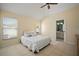 Well-lit main bedroom with a ceiling fan, two windows, and a view of the en-suite bathroom with tile flooring at 7534 Oxford Garden Cir, Apollo Beach, FL 33572