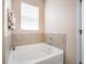 Clean bathroom featuring a white soaking tub with tiled half-wall and a window for natural light at 8518 Tidal Breeze Dr, Riverview, FL 33569