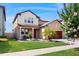 Charming two-story home featuring a manicured lawn, red garage door, and a welcoming front porch with white columns at 8747 Flourish Dr, Land O Lakes, FL 34637