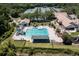 Birds-eye view of a community pool area featuring slides, a playground, and tennis courts surrounded by greenery at 9116 Woodridge Run Dr, Tampa, FL 33647