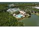Aerial view of community pool, tennis courts, and clubhouse nestled among trees and a serene lake at 9116 Woodridge Run Dr, Tampa, FL 33647
