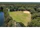 Aerial view of a large grassy ball field, with trees, adjacent to a lake in the community at 9116 Woodridge Run Dr, Tampa, FL 33647