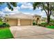 Exterior view of home with a well-manicured lawn, mature trees, and a spacious three-car driveway at 9116 Woodridge Run Dr, Tampa, FL 33647