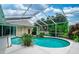 Sparkling pool with screened enclosure surrounded by tropical plants and shrubbery at 9116 Woodridge Run Dr, Tampa, FL 33647
