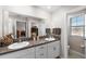 Bathroom features double sinks with granite countertops, white cabinets, a large mirror, and tiled floors at 9334 Lemon Drop Loop, Sun City Center, FL 33573