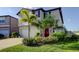 Charming two-story home featuring mature landscaping, a red front door, and a spacious two-car garage at 9334 Lemon Drop Loop, Sun City Center, FL 33573