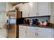 Kitchen area featuring stainless steel refrigerator, granite countertops, and sleek white cabinetry at 9334 Lemon Drop Loop, Sun City Center, FL 33573