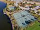Aerial view showcasing community tennis and basketball courts bordering a large lake at 9334 Lemon Drop Loop, Sun City Center, FL 33573
