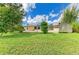 Expansive backyard with verdant lawn, utility shed, and shell landscaping leading to a screened lanai at 1857 N San Mateo Dr, North Port, FL 34288