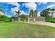Attractive home exterior with a green door, palm trees, and a well-maintained front lawn at 1857 N San Mateo Dr, North Port, FL 34288