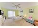 Large bedroom with a ceiling fan, light green walls, carpeted floor, and a window with sheer curtains at 1857 N San Mateo Dr, North Port, FL 34288