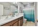 Bathroom featuring double sinks, wooden cabinets, and a shower with a blue gradient curtain at 11307 Quiet Forest Dr, Tampa, FL 33635