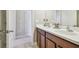 Bright bathroom featuring double sinks, white countertop, and wood cabinets with a view to the bedroom through an open door at 11307 Quiet Forest Dr, Tampa, FL 33635