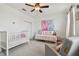 Bright Bedroom with crib, daybed, and soft gray armchair, illuminated by a ceiling fan and natural light at 11307 Quiet Forest Dr, Tampa, FL 33635