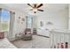 Bright Bedroom with crib, daybed, gray armchair, white dresser, and two windows allowing natural light and a ceiling fan at 11307 Quiet Forest Dr, Tampa, FL 33635