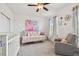 Light-filled Bedroom with daybed, crib, and gray armchair, complemented by natural light from the window and ceiling fan at 11307 Quiet Forest Dr, Tampa, FL 33635