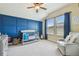 Bright Bedroom featuring a cozy gray chair, blue accent wall, and ample natural light at 11307 Quiet Forest Dr, Tampa, FL 33635