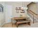 Cozy dining area featuring a wooden table, rustic bench seating, and modern pendant lights by the staircase at 11307 Quiet Forest Dr, Tampa, FL 33635