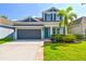 Charming two-story home features a dark gray garage, lush landscaping, and a pop of color on the front door at 11307 Quiet Forest Dr, Tampa, FL 33635
