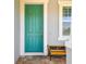 Inviting entryway with a vibrant teal front door, stone pavers, and a decorative bench at 11307 Quiet Forest Dr, Tampa, FL 33635